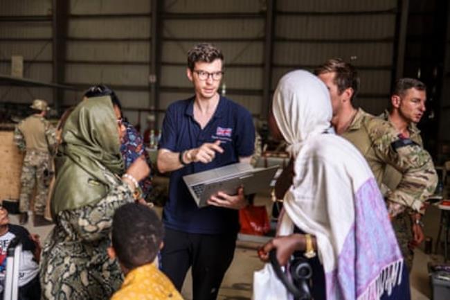 Ministry of Defence handout photo of a Foreign and Commo<em></em>nwealth Rapid Respo<em></em>nse team member helping evacuees before they fly to Cyprus from Wadi Seidna airport in Khartoum, Sudan.