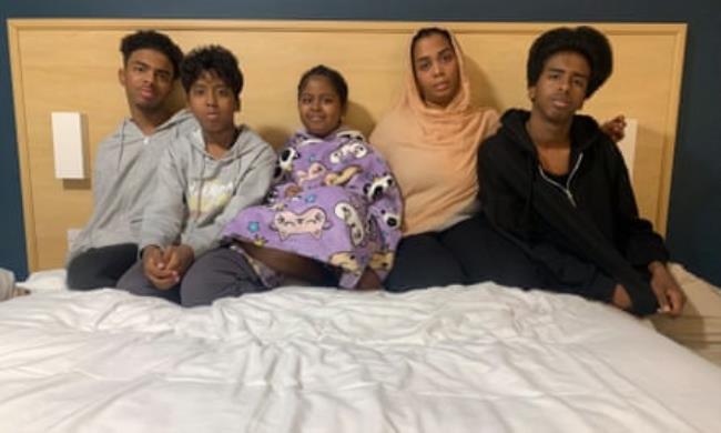 Selma Bedawi and her four children sit on a hotel bed.